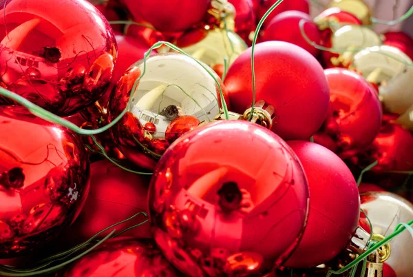 Kırmızı ve altın sarısı Noel ağacı, iple sarkıtılmış bir kutuda asılı duruyor..