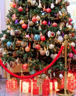 Yapay ağacın altında bir sürü mücevher ve hediye paketiyle çok güzel dekore edilmiş Noel ağacı..