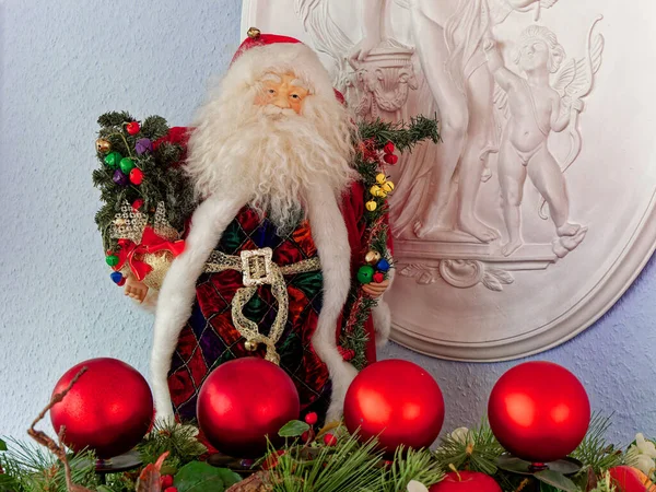 Noel Baba figürü oyma tahtasının önünde, ön planda dört kırmızı Noel ağacı topu..