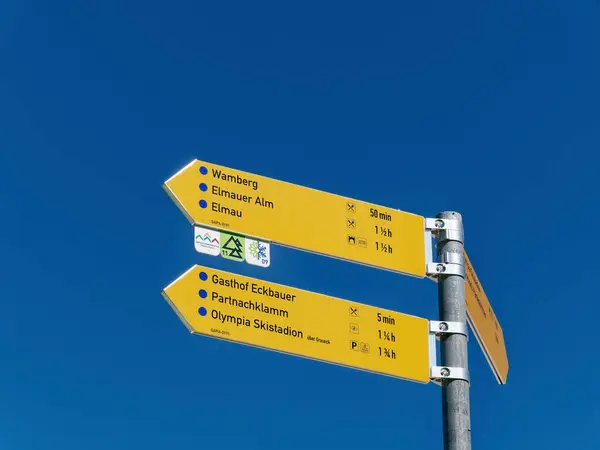 Mavi gökyüzüne, Eckbauer dağına, Garmisch-Partenkirchen 'e doğru yürüyüş işaretleri.
