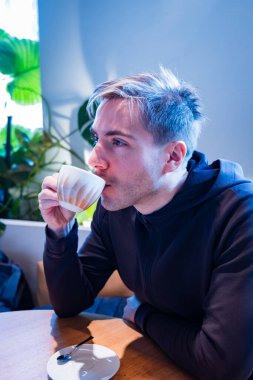 Yazılım geliştiricisi, parlak ve modern bir kafede kahvesini yudumlayan genç bir adam, bir mola sırasında modern bir kafede çalışmaya ara veriyor. Yüksek kalite fotoğraf