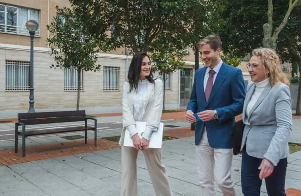 İş adamları sokakta yürüyor, konuşuyor ve gülümsüyor.