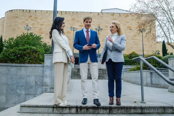İş dünyası ekibi ofis binasının dışında yeni bir projeyi tartışıyor ve fikirleri paylaşıyor.
