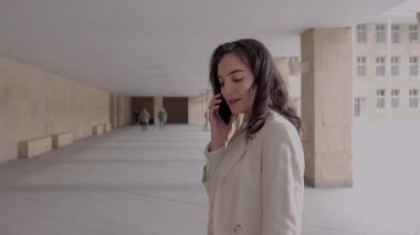 İş kadını telefonuyla konuşurken kapalı bir geçitte yürüyor.