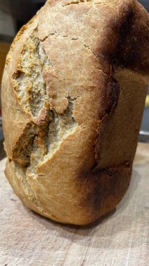 Tahta yüzeyi olan bir somun taze ekmeğin yakın plan çekimi. 