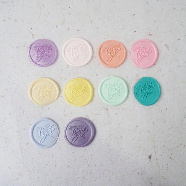 Colorful pretty wax seal stamps coin on white paper background, vintage style for wedding or invitation decoration. Top view. Flat lay.