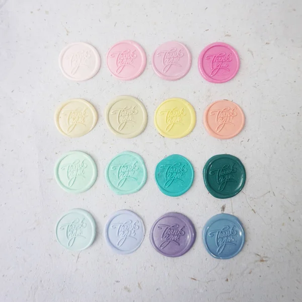 Colorful pretty wax seal stamps coin on white paper background, vintage style for wedding or invitation decoration. Top view. Flat lay.