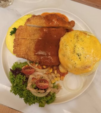 Omlet ve beyaz tabakta salata ile servis edilen kızarmış tavuk pirzolası.