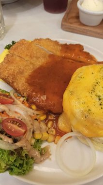 Omlet ve beyaz tabakta salata ile servis edilen kızarmış tavuk pirzolası.