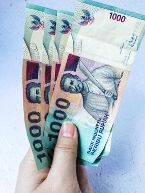 Beyaz arka planda el ele tutuşan Endonezya rupiası banknotları