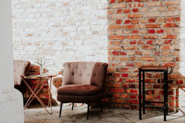 Tuğla duvar zemininde eski bir koltuk ve masa, iç tasarım konsepti, stok fotoğrafı.