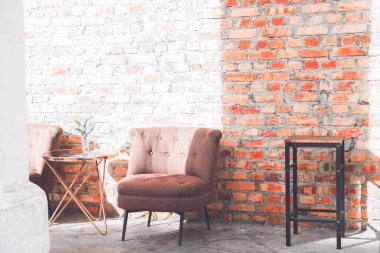 Tuğla duvar zemininde eski bir koltuk ve masa, iç tasarım konsepti, stok fotoğrafı.