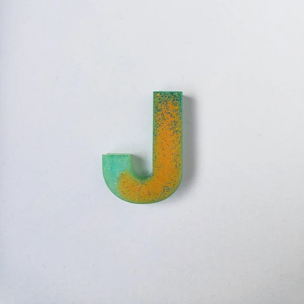 Letter J of the English alphabet made of resin on a white background