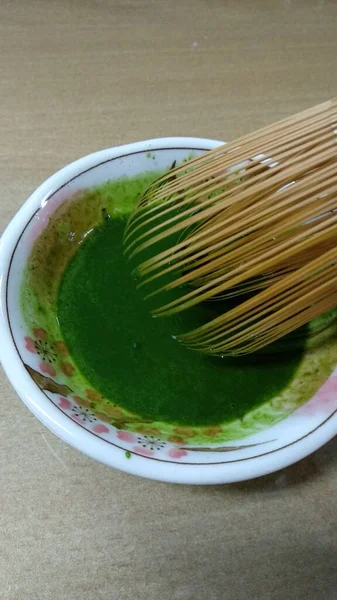 Masasında Tahta Çubuklar Olan Bir Kasede Kibrit Yeşili Çay — Stok fotoğraf