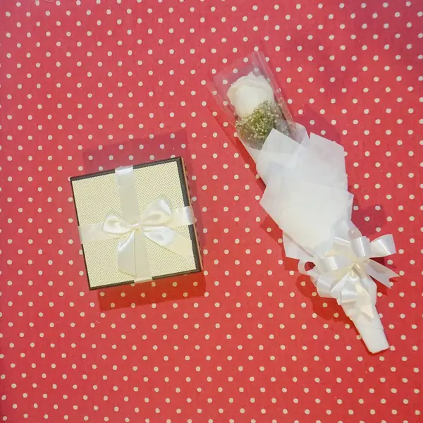a vertical shot of a white box with a bow and a bouquet of dried flowers on a white background