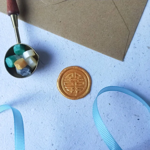 Blank envelope, wax seal stamp and sealing wax bead on blue background