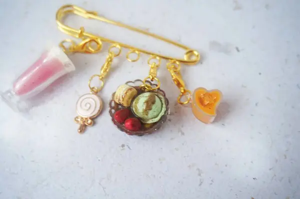 Altın bir broşa bağlanmış minyatür bir içecek ve pasta.