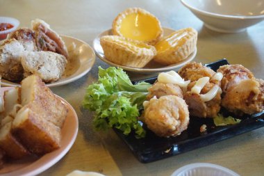 Geleneksel Çin Dim Sum 'u ahşap masada metal kasede. Masada bir sürü farklı yiyecek ve içecek var.