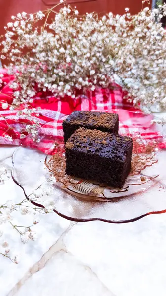 Çikolatalı kekin yakın plan fotoğrafı. Bebek nefesiyle süslenmiş şeffaf bir tabakta çikolata tozuyla tozlanmış.