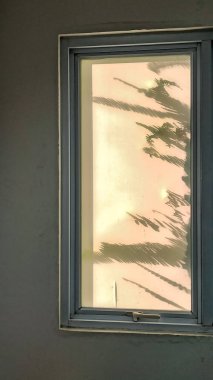 Duvarda gölgesi olan bir pencere, fotoğrafa yakın çekim.