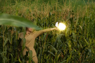 Model with a mirror in her hands outdoor in corn field. Reflection in the mirror of  elegant young woman.