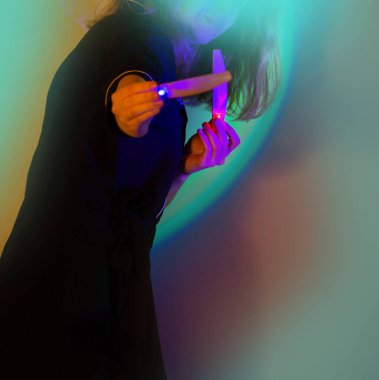 Stüdyonun arka planında neonlu genç aktif kadın tırnak sanatçısı. Renkli neon stüdyo ışığı altında duran manikürcünün portresi