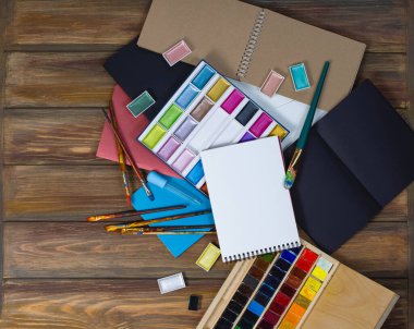 Çalışma alanı sanatçısı ya da tasarımcısı ahşap bir arka planda el sanatları aletleri kullanıyor. Albüm kopya alanı olan ahşap masa