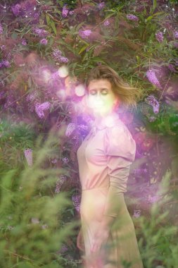 Youth and happiness concept. Positive joyful young woman near the buddleia flowers.