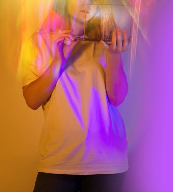 Kız, metaevrende neon arka planda sanal gerçeklik çiziyor. Kalem tutan ve şeffaf ekranda çizen genç bir kadın.