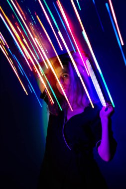 Güzel stil sahibi bir kadın sahnede neon renkli arka planda dans ediyor. Sahnede dans eden sarışın kadın model neon ışıklı arka planda..