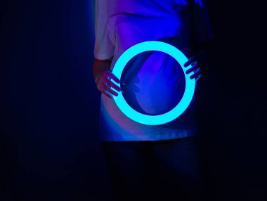 Neşeli genç kadın sahnede soyut, parlak, parlak neon ışıklarıyla dans ediyor. Sahnedeki performanslar sırasında parlak neon dansı içinde büyüleyici genç bir model..