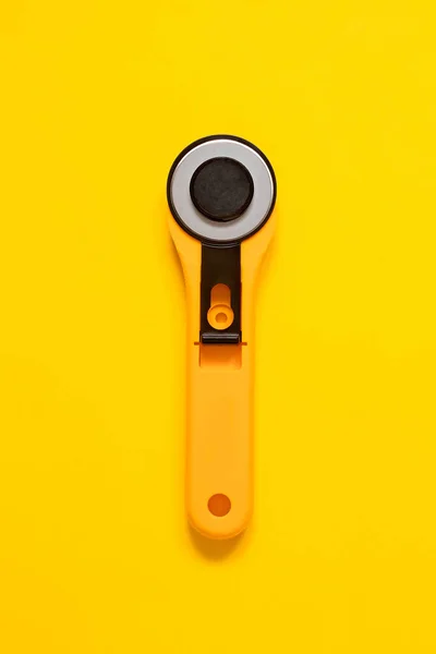 stock image Yellow black rotary knife for patchwork on a yellow background. Sewing tool. Top view. Copy space.