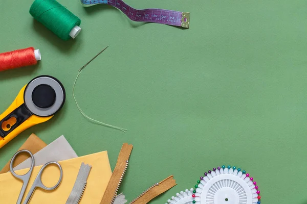 Yeşil arka planda terzilik için aksesuar dikiyorum. Döner bıçak, kumaş, makas, fermuar, iğne, iğne, iplik makarası. Düz yatıyordu. Uzayı kopyala Model.