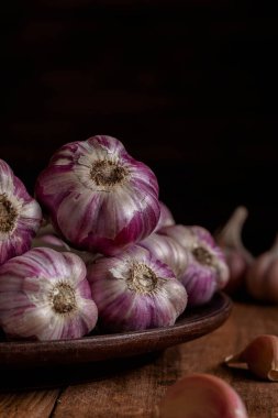 Taze mor sarımsak soğanları, ahşap bir arka planda kahverengi bir tabakta kapanıyor. Boşluğu kopyala.