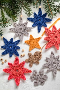 Beyaz arka planda Noel ağacı için bir sürü parlak tığ işi oyuncak var. El yapımı Noel dekoru..