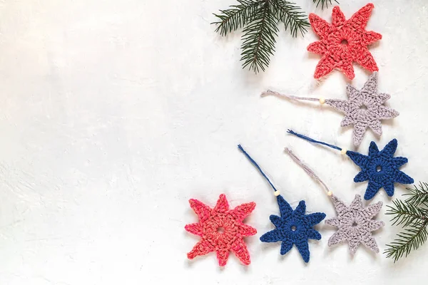 Set of grey, blue, red crochet star shaped Christmas tree toys on a white background. Copy space.