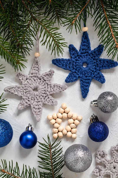 Grey blue crochet handmade Christmas tree toys , beaded star, baubles and fir branches on a white background. Handmade knitted Christmas decor. Homemade Christmas ornaments.