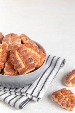 Beyaz arka planda çizgili bir peçetede Noel ağacı şeklinde bisküviler olan gri kâse. Boşluğu kopyala.