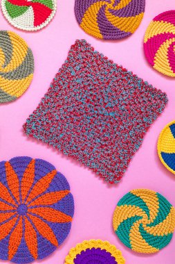 Pembe arka planda parlak renkli örgü örme bezi ve bardak altlığı. Ev yapımı. El yapımı mutfak dekorasyonu. Üst görünüm.