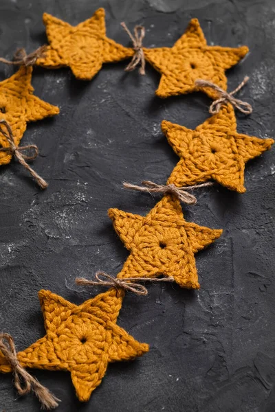 stock image Festive Christmas crochet garland on a grey background. Handmade knitted yellow stars garland. Christmas and New Year concept.