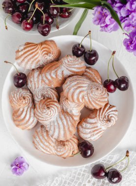 Beyaz bir tabakta taze kırmızı kirazlı kremalı kurabiye. Pudralı tereyağlı kurabiye. Üst görünüm.