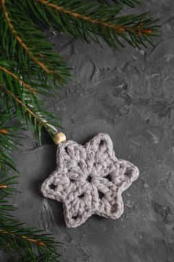 Beyaz tığ işi kar taneleri kapanıyor ve köknar dalları gri arkaplanda. El yapımı pamuklu Noel dekoru. Boşluğu kopyala.