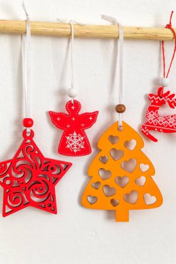 Parlak kırmızı ve sarı ahşap ağaç, yıldız ve melek bir çubukta asılı. Noel duvarı asılıydı. Alternatif Noel.