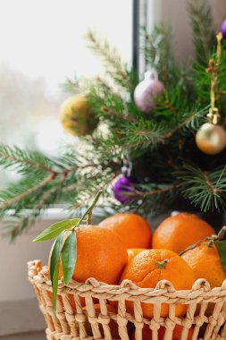 İçinde taze organik mandalinalar olan bir sepet ve noel süsü. Mandalina ya da yeşil yapraklı portakal. Sağlıklı yeme kavramı.