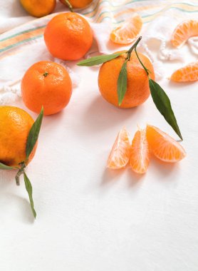 Taze sulu mandalinalar (mandalina, mandalina) ve beyaz arka planda yeşil yapraklar. Soyulmuş mandalina. Sağlıklı beslenme. Çiğ yemek. Boşluğu kopyala.