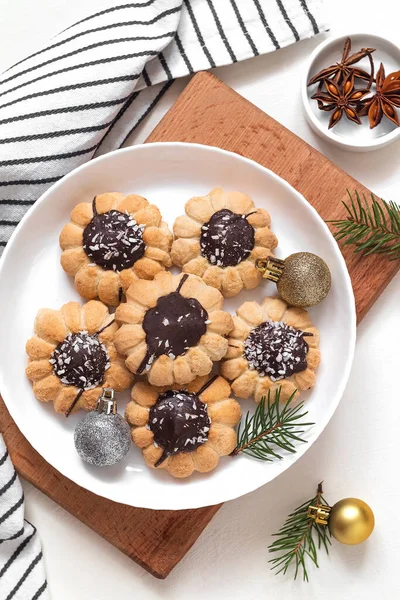 Sweet butter cookies on a plate. Flower shaped cookies with chocolate and coconut flakes with Christmas decoration.