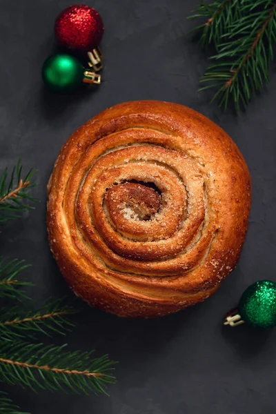 Noel tarçınlı çörek, koyu gri bir arka planda Noel süslemesi ile yakın çekim..