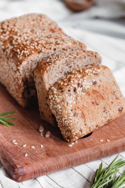 Tahta üzerinde susam tohumları olan dilimlenmiş taze ekmek. Tam tahıllı ekmeğin dokusu.