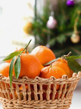 Pencere kenarında taze organik mandalinalarla dolu sepet ve Noel süsü. Yeşil yapraklı mandalina veya mandalina portakalı. Sağlıklı yeme kavramı.