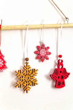 Parlak kırmızı ve sarı kar taneleri ve bir çubuğa asılı melek. Noel duvarı asılıydı. Alternatif Noel.